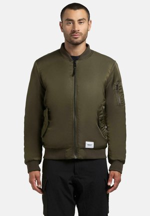 Giubbotto bomber in verde oliva, realizzato in tessuto liscio, con zip frontale, polsini a coste, tasche laterali e una piccola patch con logo sull'orlo.