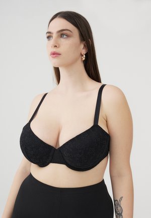 Bra in pizzo nero con coppe modellate, spalline regolabili e design senza cuciture. Abbinalo a un indumento nero a vita alta.