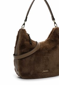 Sac à épaule en fausse fourrure marron avec une surface texturée, une sangle marron élégante et un accent logo en ton doré. Forme courbée et finition douce.
