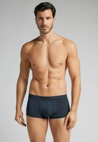 Svarta boxerkalsonger med en stretchig midjeband, som har en slät yta och en figurnära design, visade på en muskulös manlig modell.