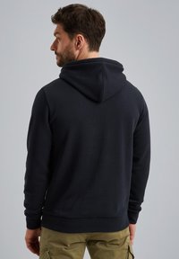 Donkerblauwe hoodie met een trekkoordcapuchon, geribbelde manchetten en zoom. Gemaakt van zachte stof, met een gladde textuur en minimalistischer ontwerp.