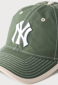 Πράσινο καπέλο μπέιζμπολ με λευκό κεντημένο λογότυπο "NY", μπεζ περίγραμμα στη γείσο και αντίθετες λευκές κεντητές λεπτομέρειες.