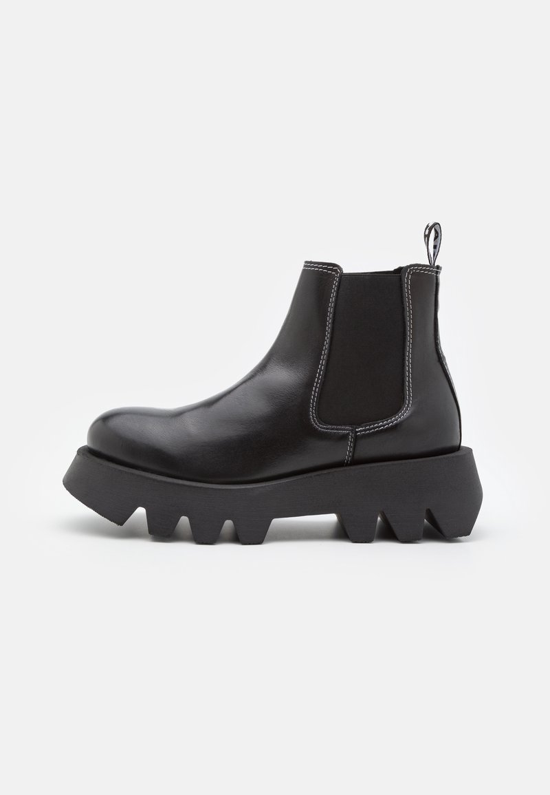 Bottes noires chevilles en cuir lisse, avec des panneaux latéraux élastiques et une semelle épaisse et crantée. Coutures blanches contrastantes.