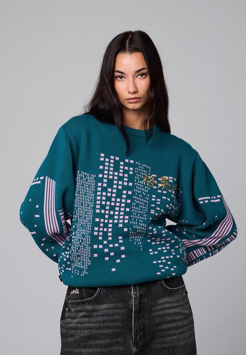Suéter de punto color azul verdoso con un patrón geométrico en rosa y blanco, con mangas oversized y un escote redondo.