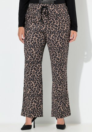 Leopardikuvioiset leveälahkeiset housut, joissa on kiristysnauha vyötäröllä, yhdistetty mustaan pitkähihainen paitaan ja mustiin teräväkärkisiin korkokenkiin.