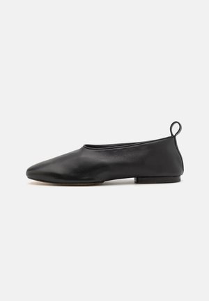 Schwarze Leder-Ballettschuhe mit spitzer Zehenform, minimalistischem Design, flacher Sohle und einer kleinen Schlaufe an der Rückseite für ein einfaches Anziehen.