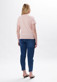 Lyserød kortærmet T-shirt i tætsiddende stil. Matchende med mørkeblå slim jeans og sorte højhælede sandaler. Glat tekstur, minimalistisk design.
