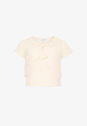 Top crema a maniche corte con sovrapposizione di pizzo, due piccoli fiocchi frontali e scollatura a goccia su sfondo bianco semplice.