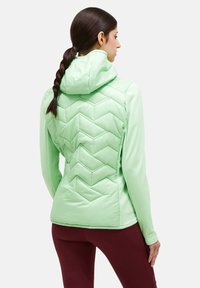 Light green insulated jacket featuring a chevron quilt pattern, a hood, and long sleeves, paired with maroon leggings.