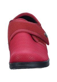 Red textile-clad shoe with a curved design, featuring a Velcro strap and textured upper. Black rubber sole for grip.
