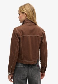Veste en coton marron avec un col, des coutures contrastantes et des poignets à bouton-pression. Tissu texturé avec une coupe ajustée. Vue arrière montrée.