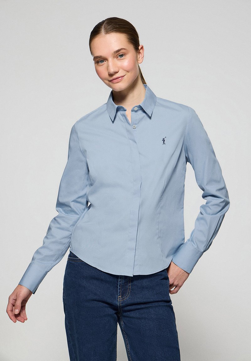 Jasnoniebieska koszula zapinana na guziki, wykonana z bawełny, z kołnierzykiem w kształcie szpicu, długimi rękawami i małym haftowanym logo na klatce piersiowej.