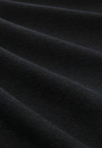 Schwarzer Stoff mit einer glatten Textur, versehen mit gefalteten Lagen, die sanfte Wellen und subtile Schattierungen erzeugen. Einheitliche Farbe über die gesamte Fläche.