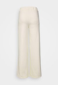 Kremowe, szerokie spodnie wykonane z miękkiego materiału; posiadają elastyczny pas i g�ładką teksturę; widoczne przeszycia wzdłuż dołu.