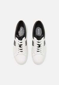 Sneakers bianchi in pelle con accenti neri e dettagli trapuntati. Presentano lati a motivo bianco e nero, punta rotonda e lacci.