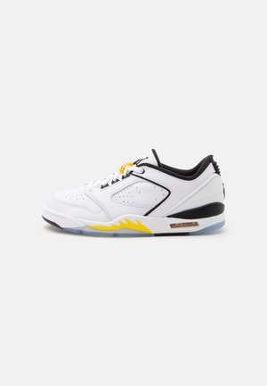 Λευκό χαμηλό sneaker με μαύρες και κίτρινες λεπτομέρειες, διάτρητο δέρμα και ορατό αερόσακο στην σόλα, εμφανίζεται από την εσωτερική πλευρά.