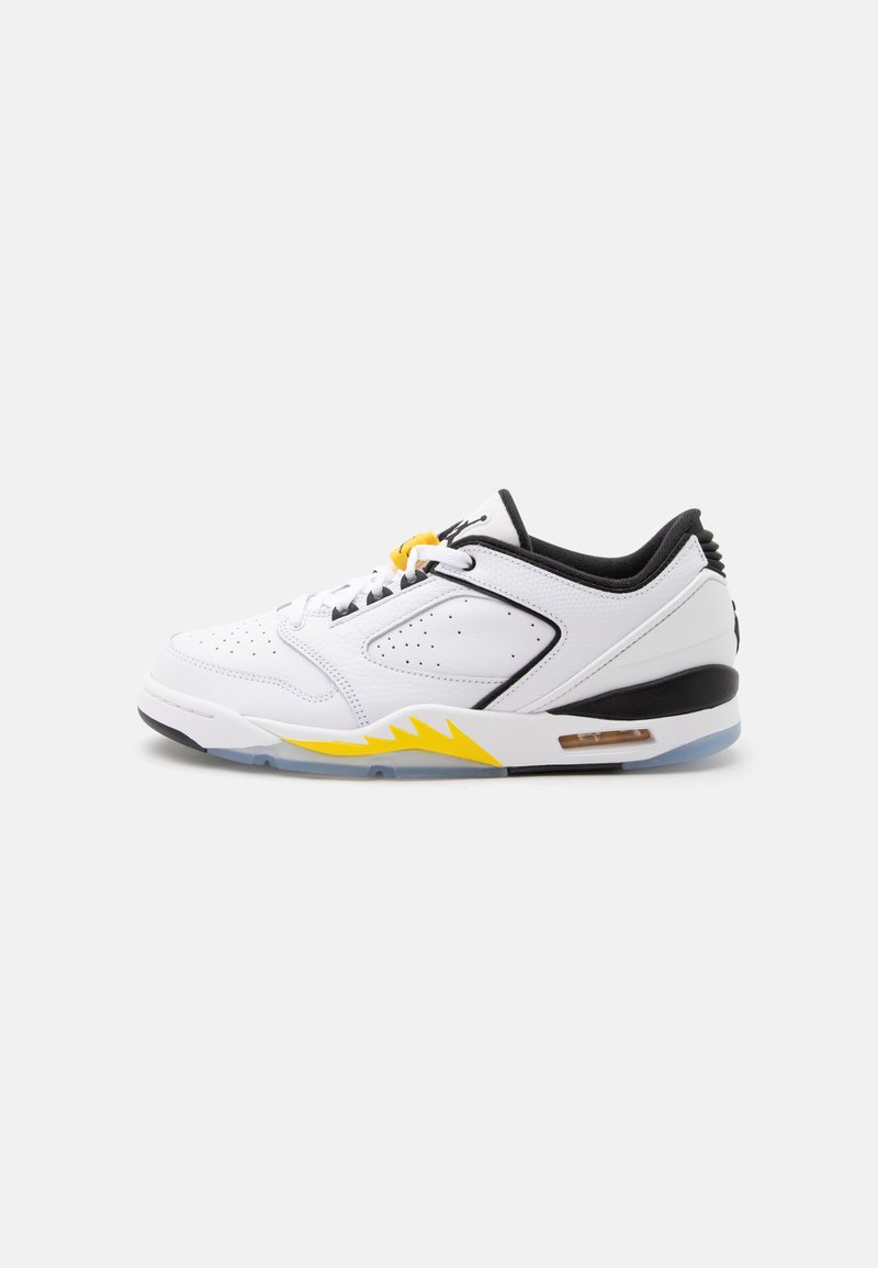 Λευκό χαμηλό sneaker με μαύρες και κίτρινες λεπτομέρειες, διάτρητο δέρμα και ορατό αερόσακο στην σόλα, εμφανίζεται από την εσωτερική πλευρά.