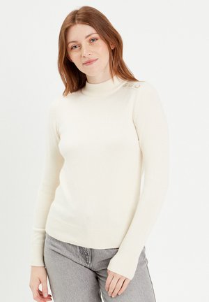 Crèmekleurige gebreide sweater met een hoge hals, voorzien van een aansluitend ontwerp, geribbelde onderkant en drie knopen op de schouder. Zachte textuur.