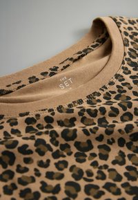 Leopardprint T-shirt in beige en zwart met een ronde hals, gemaakt van zacht materiaal, met een label waarop "THE SET" staat.