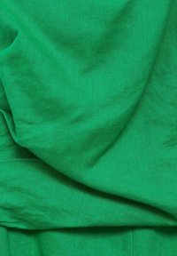 Zelená tkanina s hladkou textúrou, vo zvýraznenej jednoliatej farbe a jemnom lesku, prehodená v mäkkých záhyboch, vystihujúca prírodné vlastnosti materiálu.