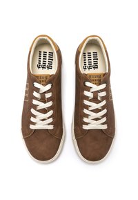 Zapatillas deportivas de ante marrón con cordones blancos, punta redondeada, detalles en color beige en la lengüeta y una plantilla con un diseño que incluye el nombre de la marca.