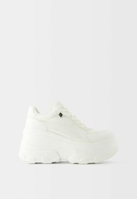 Sneaker bianche chunky con esterno in pelle liscia, suola piatta spessa, punta rotonda e un semplice sistema di allacciatura. Piccolo logo nero come accento.
