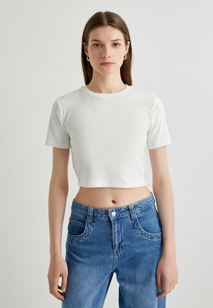 Witte cropped t-shirt van ribbelstof met een ronde halslijn en korte mouwen, gecombineerd met blauwdenim jeans met hoge taille.