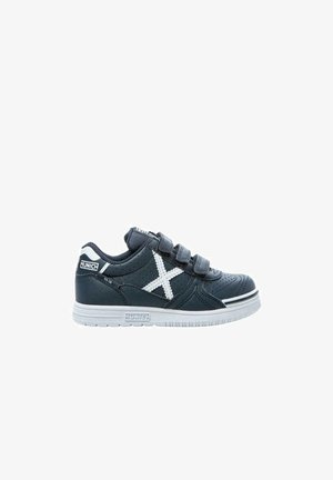 Zapatilla de deporte azul oscuro con correas de velcro, textura perforada, acentos blancos y suela de goma con una franja en contraste. Logo de la marca visible.