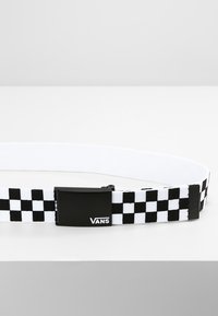 Cintura elastica a scacchi bianco e nero con fibbia in metallo nero recante il logo Vans. Testura piatta e lunghezza regolabile.