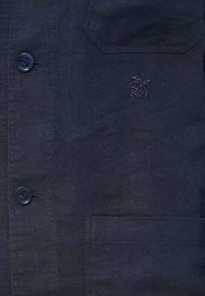 Temno modra srajca s kratkimi rokavi z dvema vidnima žepoma in izvezeno majhno logo želvice na zgornjem desnem žepu.