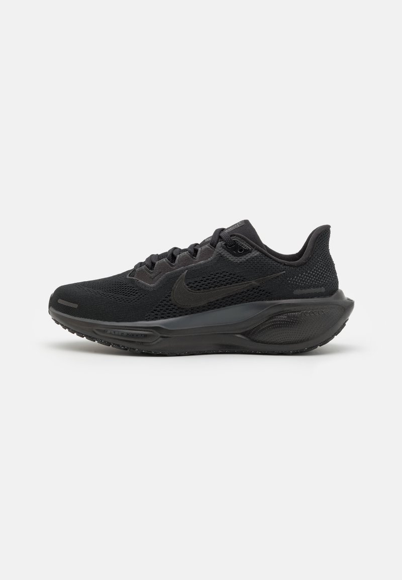 Chaussures de sport noires avec une tige en mesh, des détails texturés et une semelle rembourrée. Elles présentent un design élégant et un logo subtil sur le côté.
