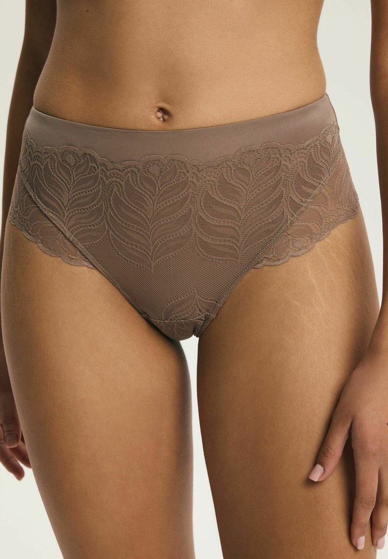 Braune Spitzenunterwäsche mit hohem Bund und Blattmustern, getragen von einer Person, die den Mittelteil und die oberen Oberschenkel zeigt, mit einer sichtbaren Hand.