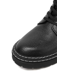 Schwarzer Lederstiefel mit strukturierter Oberfläche, Gummisohle, weißen Ziernähten und Schnürdesign. Zeigt die Spitze und den oberen Bereich.