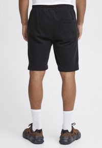Schwarze Baumwollshorts mit elastischem Bund, Seitentaschen und einer Gesäßtasche. Verfügen über eine weiche Textur und ein knielanges Design.