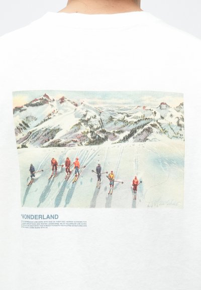 White cotton t-shirt featuring a colorful skiing scene on the back. The printed design depicts skiers on snow-covered mountains.