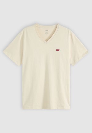 T-shirt s V-izrezom u svijetloj krem boji, izrađen od pamuka. Ima kratke rukave i mali crveni logo na lijevoj strani grudi. Glatka tekstura.