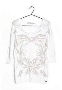 Witte trui met lange mouwen en een brede halslijn, versierd met metalen studs in bloemmotieven aan de voorkant en afgewerkt met geribbelde manchetten.