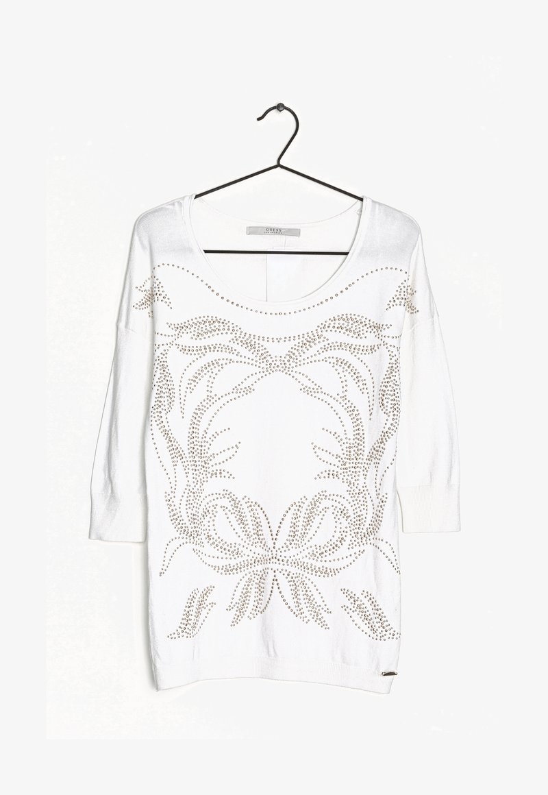 Witte trui met lange mouwen en een brede halslijn, versierd met metalen studs in bloemmotieven aan de voorkant en afgewerkt met geribbelde manchetten.