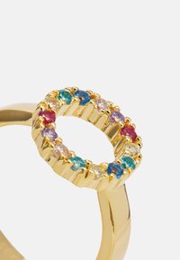Guldring med en cirkulär inställning med flerfärgade ädelstenar, inklusive röd, blå och grön, inlagda i en texturerad ring.