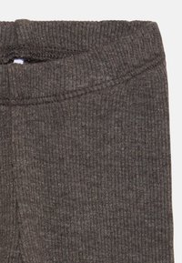 Sötét bordázott anyag, a nadrág derekának cropped nézete, amely rugalmas, sima textúrát és diszkrét fényt mutat.