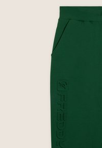 Pantaloni della tuta verdi realizzati in tessuto morbido, con una tasca laterale e logo in rilievo sulla gamba sinistra per un tocco in più.