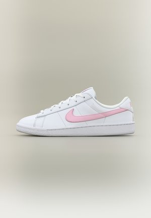 Λευκό χαμηλό sneaker Nike με ροζ λογότυπο swoosh και λευκά κορδόνια σε ουδέτερο φόντο με διαβάθμιση.