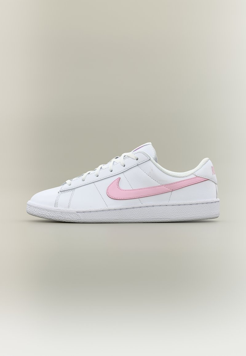 Λευκό χαμηλό sneaker Nike με ροζ λογότυπο swoosh και λευκά κορδόνια σε ουδέτερο φόντο με διαβάθμιση.