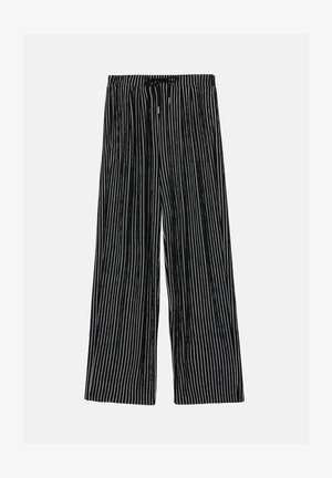 Črne in bele proste hlače širokega kroja iz mehkega materiala, z elastičnim pasom in vrvico za prilagoditev velikosti.