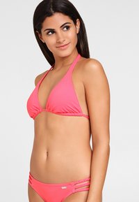 Heldere roze bikini met een driehoekige top en verstelbare banden. De onderkant heeft gevlochten zijaccenten. Glad, rekbaar materiaal.