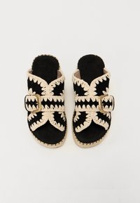 Sandali neri in suede con accenti intrecciati color crema, caratterizzati da una larga cinghia con fibbia e un bordo goffrato e trecciato.