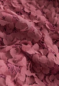 Raspberry lace fabric with a floral pattern, featuring textured, petal-shaped cutouts and a delicate mesh background.