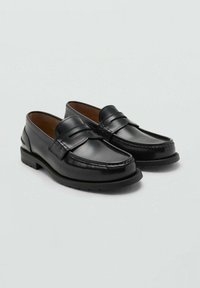 Mocasini din piele neagră cu un finisaj neted, vârful rotund și cusături ridicate. Au o talpă din cauciuc durabilă, joasă și o curea decorativă pe partea superioară.