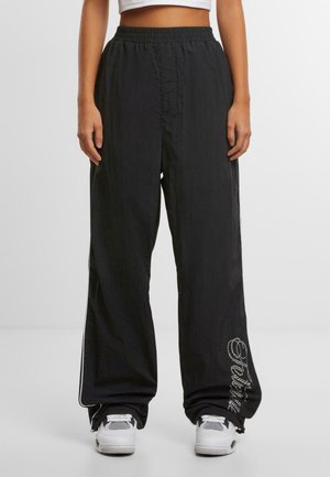 Zwarte wijde broek gemaakt van lichtgewicht stof, met een elastische tailleband en een decoratief ontwerp in strass op het onderbeen.