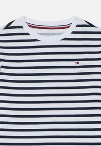 Navy and white striped cotton t-shirt with a crew neck and small embroidered logo on the chest. Smooth texture and short sleeves.